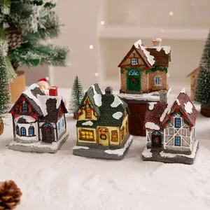 Vista dettagliata di quattro case in miniatura di Natale in resina con neve e ghirlande reali