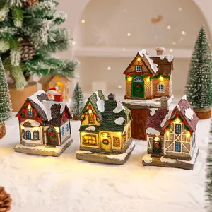 Vista dettagliata di casette di Natale in resina illuminate poste sulla neve finta