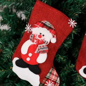 Detalle de un calcetín de Navidad de lino rojo con un muñeco de nieve colgado de un árbol