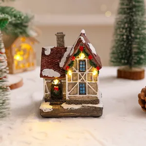 Primo piano di una casa di Natale in resina con luci LED calde sulla neve finta