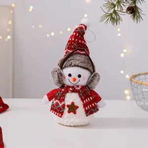 Primer plano de un lindo muñeco de nieve de peluche con gorro rojo y orejeras de piel sintética.