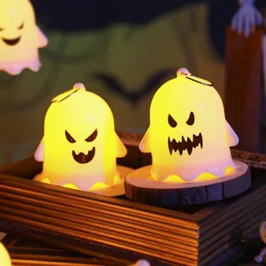 Detail view of two glowing Halloween ghost night lights with cute spooky faces on wooden base