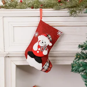 Detalle de un calcetín de Navidad de lino rojo con aplique de oso en una chimenea.