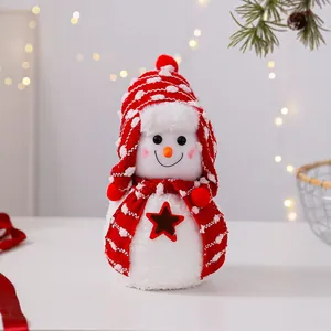Primer plano de un lindo muñeco de nieve de peluche con gorro y bufanda rojos