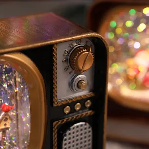 Macro view of retro Christmas TV snow globe with vintage knobs and warm festive lights