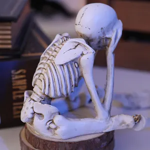 Detailed close-up view of a white resin skeleton figurine in a pensive sitting pose