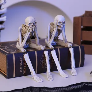 Halloween skeleton figurines with dangling legs sitting on a vintage book decoration