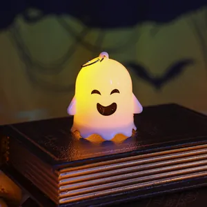 Glowing cute ghost night light Halloween decoration placed on dark vintage books