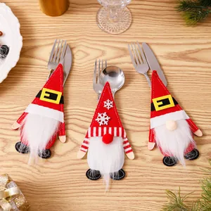 Drie schattige kerstkabouter bestekhouders voor vorken en messen op een feesttafel.