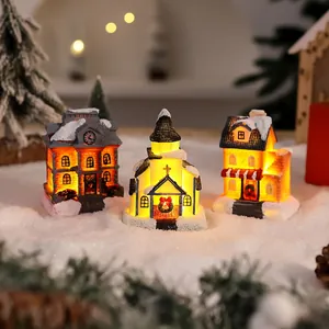 Miniature glowing Christmas village houses with warm LED lights and artificial snow