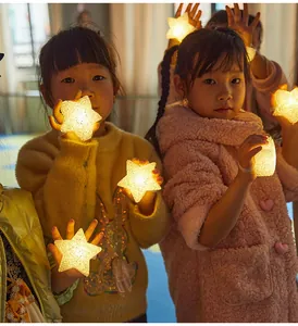 Adorable children holding warm glowing LED star lights for festive stage performances