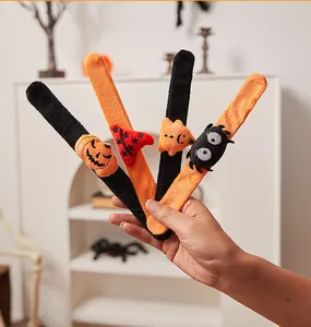 Gedetailleerd overzicht van pluche Halloween slap bracelets met pompoen- en spinmotieven.