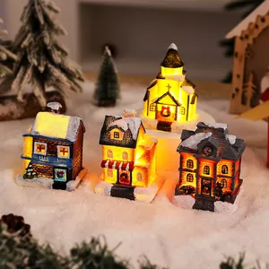 Miniature glowing resin Christmas village houses with snowy roof and warm LED lights