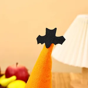 Detailed view of Halloween gnome decoration with bright orange felt hat and black bat topper