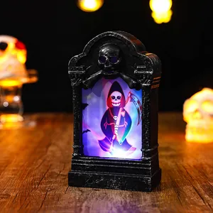 Close-up of glowing Halloween tombstone lamp featuring a grim reaper illustration