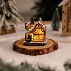 Casetta di Natale in miniatura in resina luminosa con tetto innevato su base di legno vero.