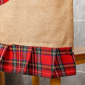 Macro view of Christmas chair cover detail with rustic burlap and red plaid pleated hem.