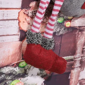 Close-up detail of red felt Christmas gnome boots with grey faux fur and striped legs