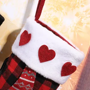 Close-up of red and black plaid Christmas stocking with heart accents on white fur cuff