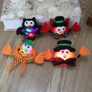 Detail van vier oplichtende Halloween-broches met pompoen- en vleermuisontwerpen op hout.