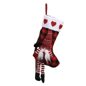 Red and black plaid Christmas stocking with cute gnome and hanging legs decoration.