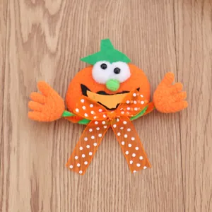 Detailopname van pluche Halloween pompoen broche met gestipte strik en groene hoed.