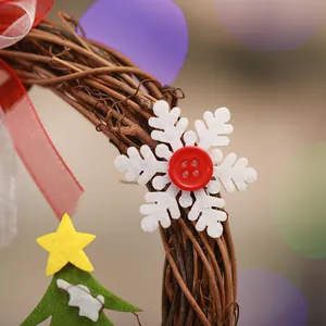 Close-up of white felt snowflake and red ribbon on a rustic vine Christmas wreath.