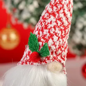 Détail d'un ornement de gnome de Noël tricoté rouge et blanc avec une feuille de houx