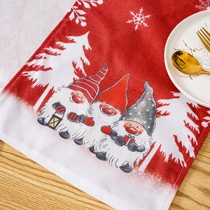 Detail view of festive red Christmas table runner with gnome pattern and white trees.