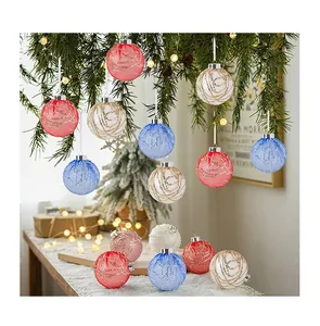 Boules de Noël festives en filet de paillettes suspendues à une branche de pin vert.