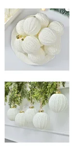 Close-up of white knitted Christmas ornament balls with golden caps hanging from a green garland