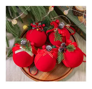 Elegantes bolas de Navidad rojas flocadas con piñas y cintas de terciopelo en bandeja de madera