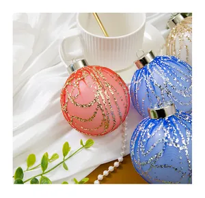 Gros plan détaillé de boules de Noël colorées avec tulle à paillettes sur fond de tissu blanc.