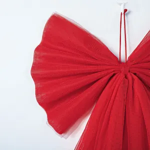 Detail shot of oversized red organza Christmas bow decoration with sparkle mesh texture.