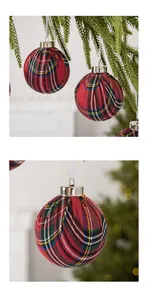 Close-up of red plaid fabric Christmas ball ornaments hanging on a pine tree branch.