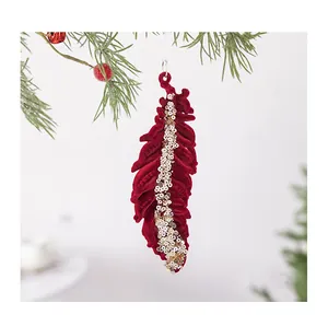 Gedetailleerd overzicht van rood geflokte kerstveer-ornament met gouden lovertjes