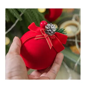 Primer plano de una bola de Navidad roja flocada con lazo y detalle de piña de pino