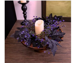Detalle de corona de hojas de arce negras artificiales con bayas moradas y vela