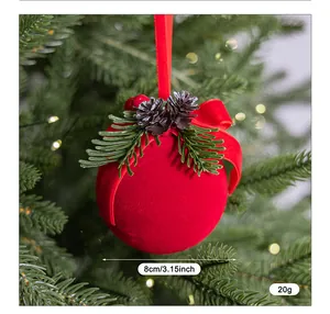 Vista detallada de bola de Navidad roja flocada con piñas y un lazo de terciopelo