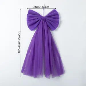 Decorative large purple mesh bow with long streamers for festive window or wall hanging display.