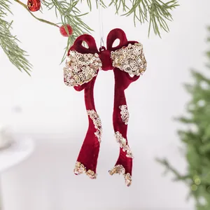 Feestelijke rode fluwelen kerststrik met gouden pailletten hangend aan een boomtak