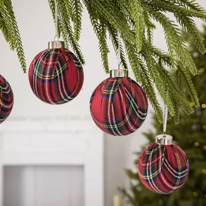 Set of festive red plaid Christmas ball ornaments hanging on a green pine branch