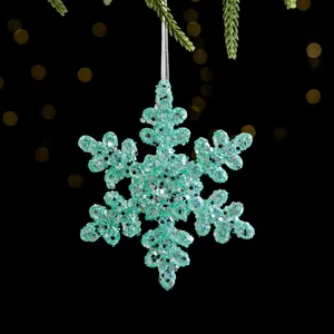 Funkelnde hellblaue Pailletten-Schneeflocke als Weihnachtsbaumschmuck am Tannenzweig