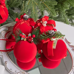 Elegantes bolas de Navidad flocadas rojas con lazos festivos y piñas sobre un espejo