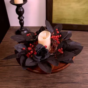 Corona de Halloween de hojas de arce negras con bayas rojas y vela para la mesa
