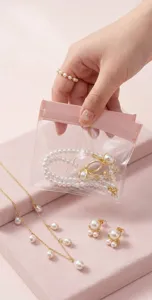 Vista detallada de bolsa de joyería transparente con sello rosa y collar de perlas