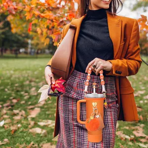 Set accessori per bicchiere arancione con manico intrecciato e pompon in parco autunnale