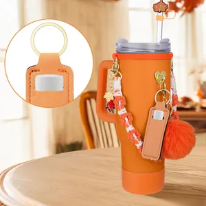 Dettaglio del set di accessori arancioni per bicchiere con porta rossetto e pompon.