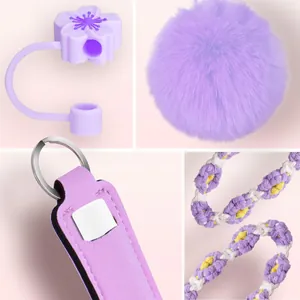 Dettaglio di copri cannuccia a fiore di ciliegio viola, pompon e set portachiavi rossetto.