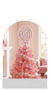 Close-up of a pink lollipop Christmas tree topper decoration in a cozy room setting.
